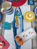 Table setting with colorful plates, cups, and coasters on a wooden table.